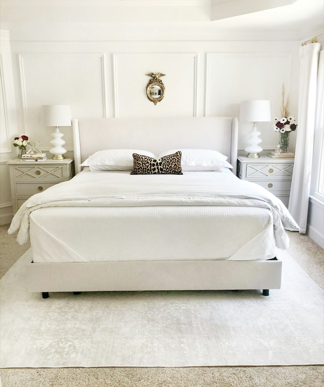 Bed made with white linens between two nightstands with lamps