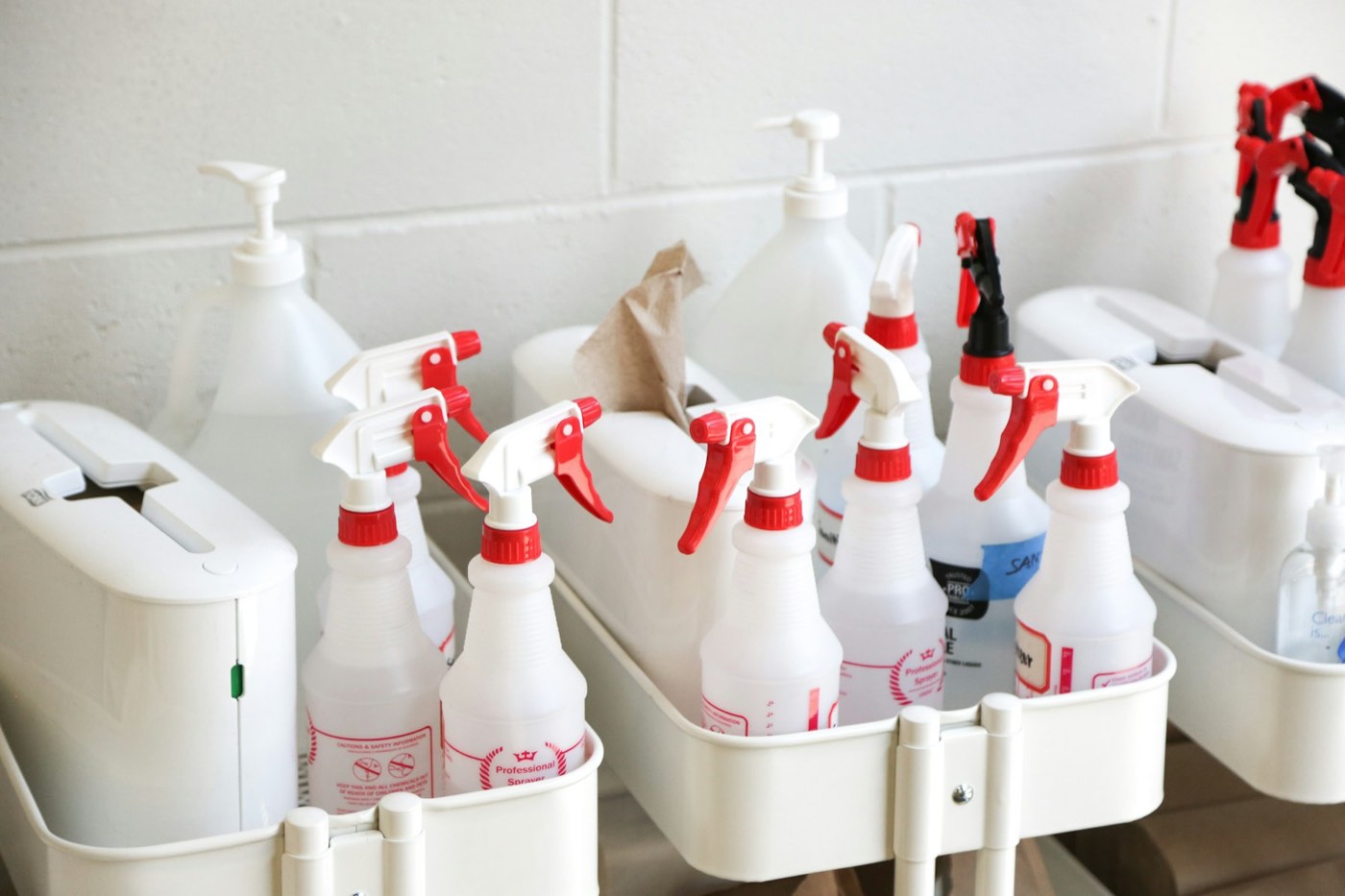 Two white caddies packed with spray bottles and cleaning products